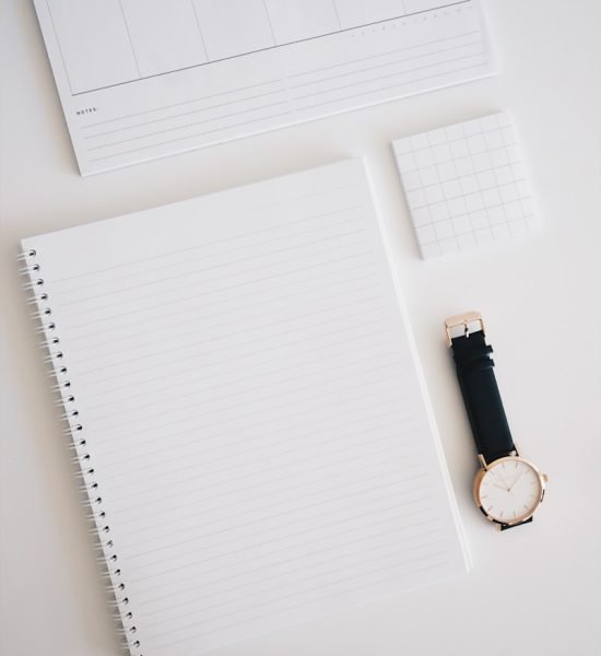 round analog watch with black leather strap on top of white wooden surface